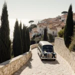 Funeral procession moving along white stone path toward turquoise Mediterranean Sea with cypress trees and golden sunset glow
