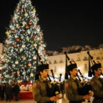 Scouts play bagpipes beside a giant lit Christmas tree in Bethlehem