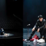 Bowen Yang sitting alone on dim SNL stage with spotlight and scattered costume props for farewell