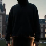 Lone suspect standing under shadow of Brown University building with dusk light and police tape.