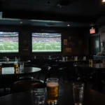 Sports bar showing muted College Football Playoff screens with dimmed lights and empty chairs