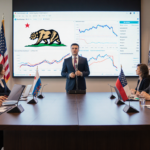 Conan Nolan speaking to a diverse panel at a wooden table with California flags and a screen of maps and graphs