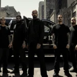 Group of tattooed men standing in front of a black SUV with Puente-13 and open rear doors revealing evidence bags
