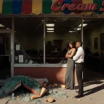 Tyra Banks standing with crossed arms and Louis Martin beside her in front of a shuttered ice cream shop with broken awning a