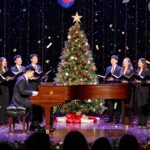 Ponpon Chen Jazz Quartet playing piano with festive lights and a live Christmas tree while confetti swirls.