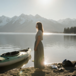 Woman crying standing on Lake Perris shore with sunlit face and a capsized kayak behind her amid quiet blue mountains.