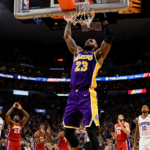 LeBron James soaring for a slam dunk with his glistening Lakers jersey under bright arena lights and stunned 76ers fans.