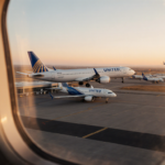 United planes taking off from McClellan‑Palomar Airport at sunset with terminal seen through a midair window and a landing je