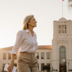 MacKenzie Scott walking toward camera with golden hour light over CSUN library and holding a donation envelope for education