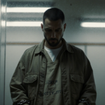 Prisoner Nick Reiner looks down with shackled hands in a courtroom glass wall guilt heavy