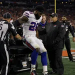 Quinshon Judkins is lifted off the field by medical staff with a splinted leg and teammates watching in a stadium