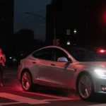 Silver car speeding past red traffic light with TikTok livestream on driver