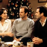 Jerry Seinfeld talking with Julia Louis‑Dreyfus with Larry David watching and a glowing Christmas tree in background