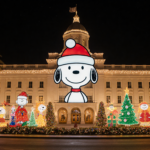 Snoopy smiling with holiday lights illuminating City Hall on a winter evening