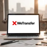 Laptop displays WeTransfer logo with red X on a minimalist desk with scattered creative tools and a blurred cityscape behind