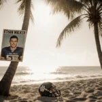 Abandoned football helmet rests on Orlando beach sand with faded Ethan Walker poster hanging from palm tree