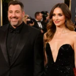 Adam Sandler and wife Jackie walk the red carpet with matching black outfits and golden light highlighting their smiles