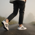Woman walking down a dawn path with Adidas handball sneakers and misty atmosphere
