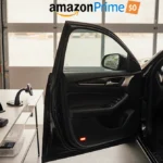 New car parked at garage with Amazon Prime logo above and wireless charging phone visible inside open door