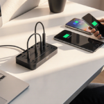 Desk organized around sleek Baseus charging station with laptops and phones charging in natural light.
