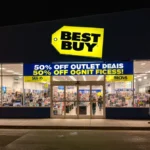 Shoppers browsing Best Buy outlet deals with 50% off banner and bright electronics displays