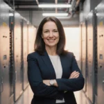 Beth Wozniak stands confidently before a modern electrical panel with sleek equipment and warm lighting showing her expertise
