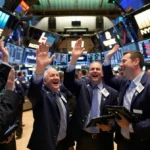 Investors celebrate Bitcoin price surge with high-fives and handshakes under bright trading floor screens