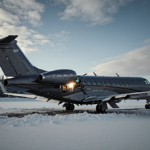 Damaged Bombardier Challenger 650 plane sitting on crash site runway with wings torn and snowy Bangor Airport in background