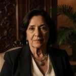 Brazilian woman sits with determination showing BDSM accessories and tropical luxury living room behind