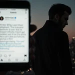 Brooklyn Beckham stands alone facing city skyline with blurred phone showing Instagram post and moody dusk lighting