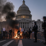 Protesters clash with riot police near the Capitol dome holding signs with smoke and flashing lights.