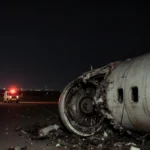 Cargo plane lies wrecked on runway with emergency vehicles responding and damaged engine exposed