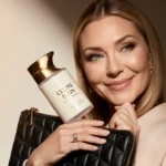 Celine Dion holding luxury hand cream with elegant packaging showing creamy texture and designer purse