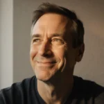 Chris Noth smirks at camera with warm natural light on his face and blurred cityscape behind