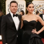 Chris Pine and Keana Sky Wenger posing together on the Golden Globes red carpet with golden lighting and elegant formal attir