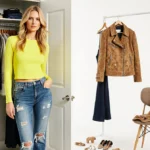 Model wearing bright yellow top with distressed denim jeans stands near brushed jacket and crop pants on chair