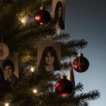 Christmas tree glowing with family photos and mementos with single ornament on floor