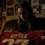 Claire Kittle sits alone with 49ers jersey and sports photos showing the emotional impact of her injury