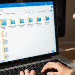 Person organizing computer files with organized folders visible on screen and hands on keyboard