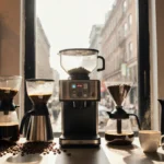 Coffee shop counter displays brewing equipment with grinders and cups arranged around central workspace and natural light