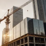 Construction crane working at data center site with glass building and skyscrapers behind