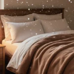 Plush queen comforter drapes over bed with golden light from coffee cup and snow falling outside window