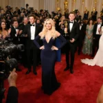 Chelsea Handler stands on carpet with cams and celebrities near Timothée Chalamet holding his award