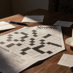 Completed crossword puzzle spreads across wooden table with warm light and a steaming morning coffee nearby