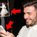 Cruz Beckham laughs at phone screen with blurred Victoria Beckham dance photo and red arrows behind him