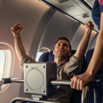 Passenger raising arms with hand on beverage cart and flight attendant