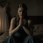 Elizabeth Smart praying with clasped hands and candlelight showing wedding dress outline in dim room