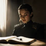 Emilia Clarke sits alone with tears on her cheeks and abandoned notebook on wooden table