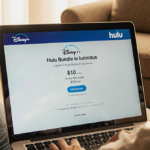 Person sits on couch using laptop with Disney Plus and Hulu bundle offer showing $10 first month $13 thereafter and soft glow