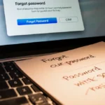 MacBook login screen showing forgot password link with keyboard and notepad nearby